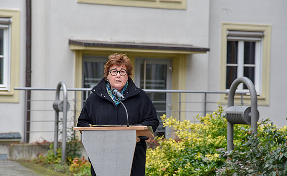 Sozialministerin steht am Rednerpult im Innenhof des Landtags