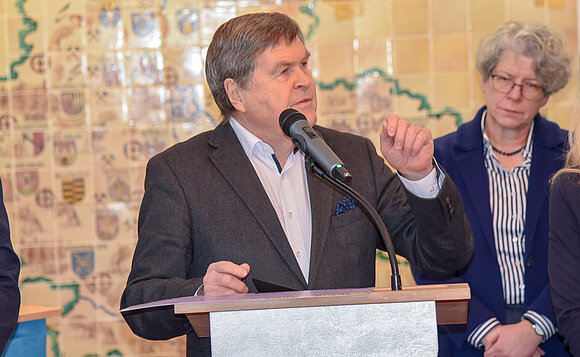 Dieter Steinecke, Vorsitzender des Landesverbands Sachsen-Anhalt im Volksbund Deutsche Kriegsgräberfürsorge spricht am Rednerpult zur Spendenübergabe.