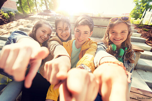 Gruppenbild von fröhlichen Jugendlichen, die mit dem Finger in die Kameralinse zeigen.